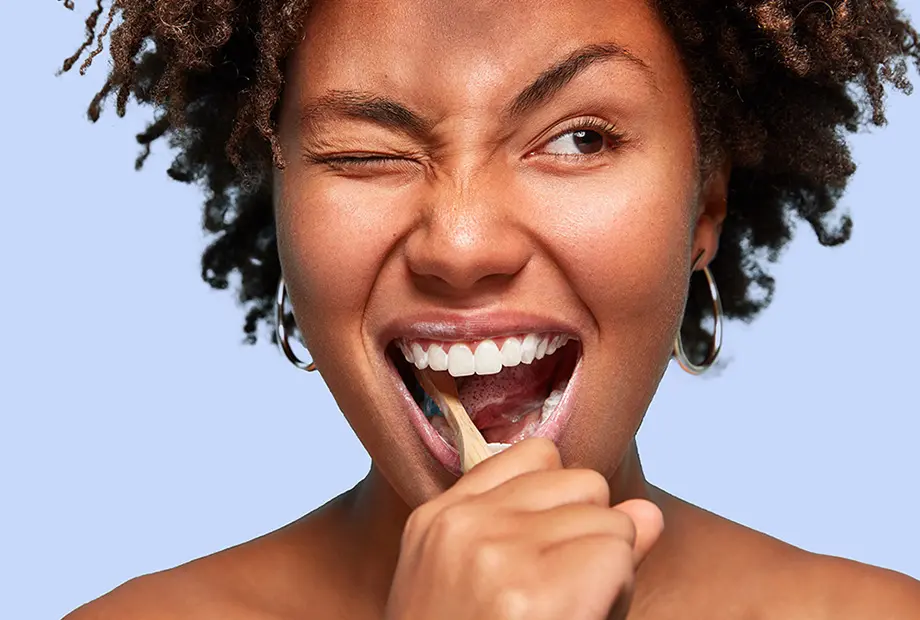 Frau putzt sich die Zähne und zwinkert